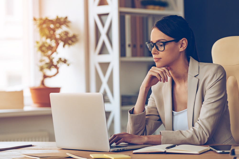 A woman with glasses uses her laptop to retrieve her NPN.