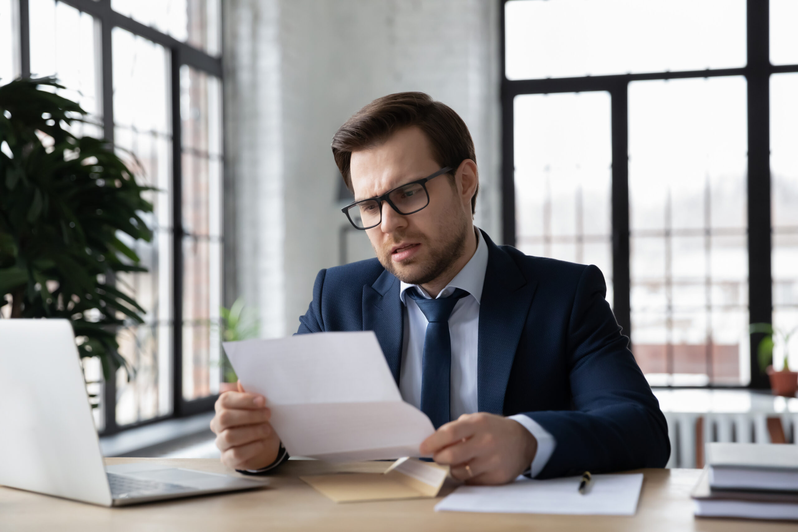 A man in a blue suit reads a notice that his CPA license is under investigation.