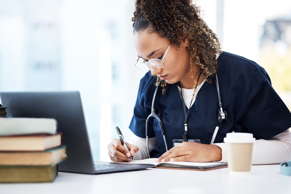 nurse studies with books and coffee nearby