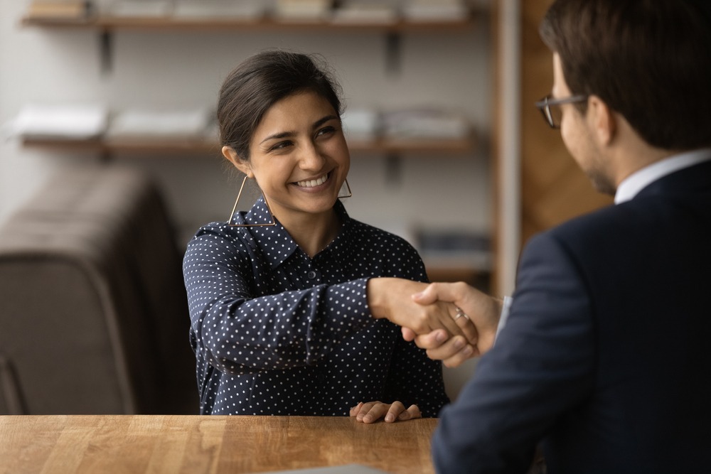 A CPA license defense lawyer sits across the desk from and shakes hands with a client seeking license reinstatement.