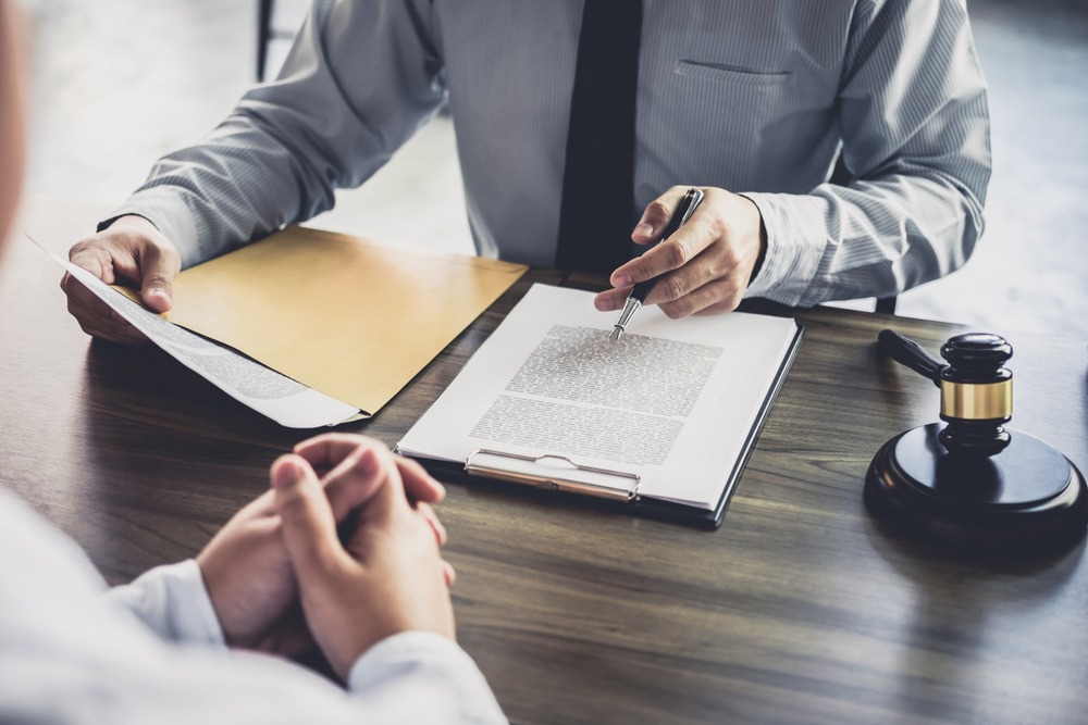 A lawyer points at a document and sits across the desk from a law enforcement license defense client.