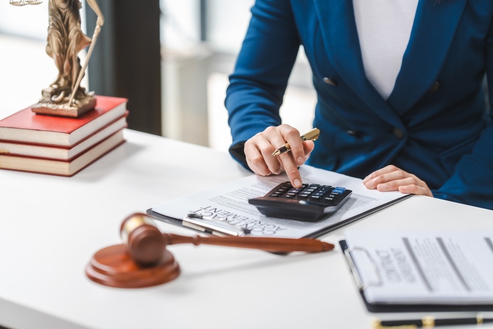 A professional license defense lawyer using a calculator to add up their legal fees and provide a client with the cost of their service.